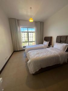 zwei Betten in einem Hotelzimmer mit Fenster in der Unterkunft هبة مارينا مدينة الملك عبدالله الاقتصادية in King Abdullah Economic City