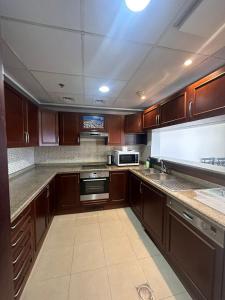 eine Küche mit Holzschränken und einem Herd mit Backofen in der Unterkunft هبة مارينا مدينة الملك عبدالله الاقتصادية in King Abdullah Economic City