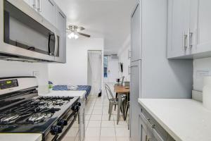 a kitchen with white cabinets and a stove top oven at Steps 2 Beach, Prime Ocean Dr Condo w/2 Queen Beds in Miami Beach