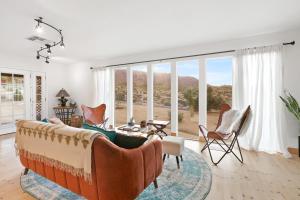 a living room with a couch and chairs and windows at High View Haven - Hot Tub, Fire Pit, BBQ in Joshua Tree! home in Joshua Tree