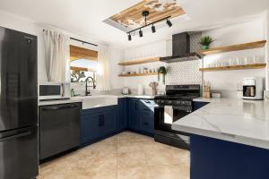 a kitchen with blue cabinets and a black refrigerator at Modern Desert Escape - Fire Pit, BBQ and Design! home in Yucca Valley