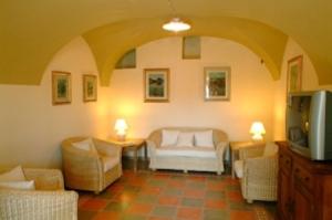 a living room with a couch and chairs and a tv at Corte Fiorita Albergo Diffuso in Bosa