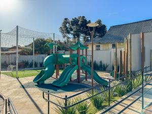 a playground with a green slide in a yard at Apartamento Viña del Aire 1 dorm by Achei Gramado in Gramado