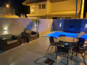 un patio avec une table et des chaises à côté d'une piscine dans l'établissement Casa 3 Condomínio Pé na Areia Ponta do Papagaio, à Palhoça