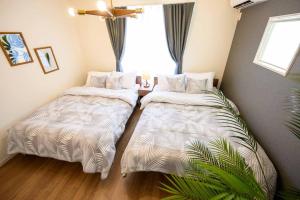 a bedroom with two beds and a window at Paradiso北谷 in Okinawa City