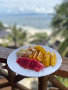 a plate of fruit on a table with the ocean in the background at Siquijor Plage Inn in Siquijor