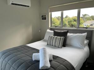 a bedroom with a large bed with two windows at STAY WITH US RAGLAN - Studio in Raglan