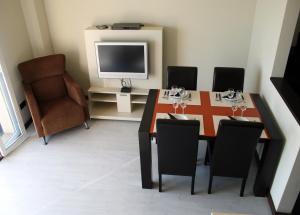 comedor con mesa, sillas y TV en Sealand Apartment, en Les Cases d'Alcanar