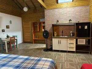 a room with a bed and a kitchen and a table at Suítes Vila Jjae in Praia do Rosa
