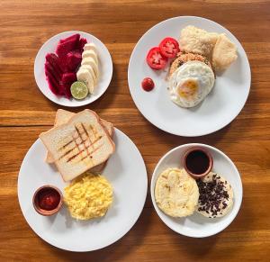 4 assiettes de produits pour le petit-déjeuner sur une table en bois dans l'établissement Lime Penida Cottages, à Nusa Penida