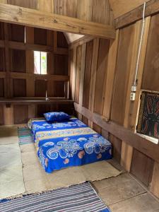 a room with two beds in a room with wooden walls at Authentique Homestay in Rantepao
