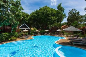 a pool at a resort with chairs and umbrellas at Harry's Bungalows in Mae Nam