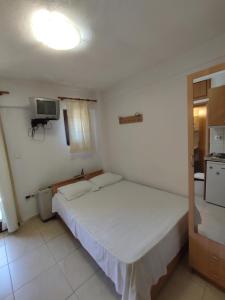 a bedroom with a white bed and a television at Studios Kapsalas Thessaloniki in Thessaloniki