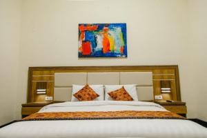 a bedroom with a bed with a painting on the wall at Musafir Guest House Syariah in Solo