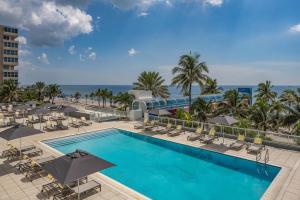a pool with chairs and umbrellas and the ocean at The Westin Fort Lauderdale Beach Resort in Fort Lauderdale