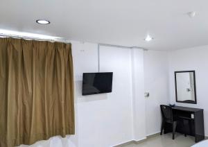 a room with a television on a wall with a desk at EnE Sri Cemerlang in Kota Bharu