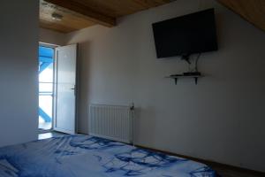 a bedroom with a bed and a tv on the wall at Casa Pescarului La Maxea in Sfântu Gheorghe