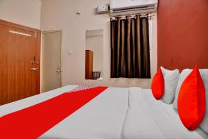 a bedroom with a large bed with red pillows at Hotel O Sudipti Resort in Indore