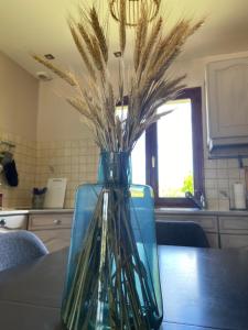 a glass vase with some grass in it on a table at Terre et Mer, maison avec jardin in Quend