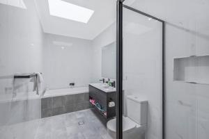 a bathroom with a shower and a toilet and a sink at Sandy Feet Retreat in The Entrance