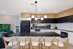 a kitchen with a dining table and white chairs at Sandy Feet Retreat in The Entrance