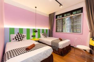 two beds in a room with pink and green stripes at Parkland Suites in Brinchang