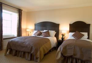 1 dormitorio con 2 camas y ventana en Baileys Hotel Cashel, en Cashel