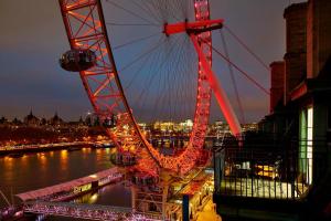 a large ferris wheel is lit up at night at London Marriott Hotel County Hall in London