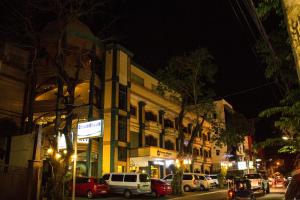 Eine Stadtstraße bei Nacht, vor deren Gebäude Autos geparkt sind in der Unterkunft Crown Royale Hotel in Balanga