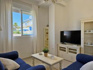 - un salon avec une télévision et un canapé bleu dans l'établissement Apartamento Playa Ballena - Ole Solutions, à Costa Ballena
