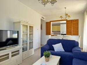 un salon avec un canapé bleu et une télévision dans l'établissement Apartamento Playa Ballena - Ole Solutions, à Costa Ballena
