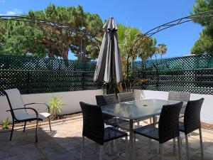 patio ze szklanym stołem, krzesłami i parasolem w obiekcie Apartamento Galeón - Ole Solutions w mieście El Puerto de Santa María