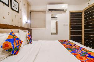 a bedroom with a bed with a colorful blanket on it at FabHotel Shree Ram Palace in Indore