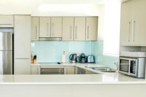 a white kitchen with white cabinets and appliances at Hamptons Style Penthouse at Kings Beach in Caloundra
