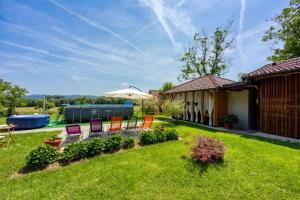 a yard with chairs and a table and an umbrella at Merry's House w/ Pool, Sauna & Jacuzzi - Happy Rentals in Griblje