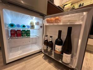 an open refrigerator filled with bottles of wine at Cosy, self-contained guest house in Thornton Heath +6 photos