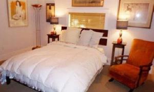 una camera da letto con un letto bianco e una sedia di Northside Hideaway Exquisite1-Bedroom House, Quiet Street, a Bozeman