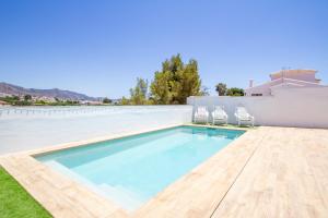 a swimming pool with two chairs and a house at Villa RUBI in Nerja