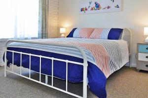 a bedroom with a bed with a blue and white blanket at Allara 1 in Merimbula