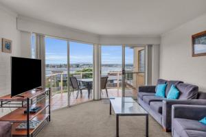 a living room with a couch and a tv at Baywatch 5 in Merimbula