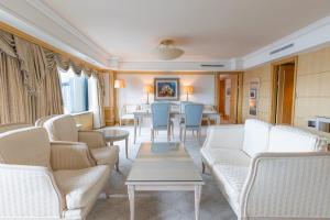 a living room with white furniture and blue chairs at Lotte Hotel Busan in Busan