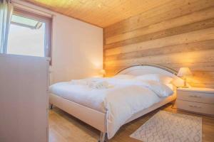 a bedroom with a white bed with a wooden wall at Chalet avec vue in Nendaz