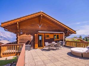 a log cabin with a deck with a table and chairs at Chalet avec vue in Nendaz