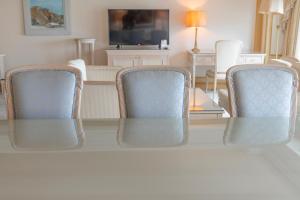a living room with three chairs and a television at Lotte Hotel Busan in Busan