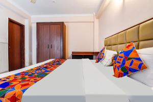 a bedroom with a large white bed with a colorful blanket at FabExpress Central Plaza in Dehradun