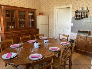 a kitchen with a wooden table with chairs and a refrigerator at Le petit gîte du theil au servant in La Chapelle-Viviers