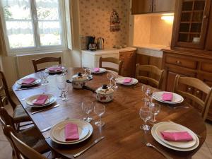 a wooden table with plates and wine glasses on it at Le petit gîte du theil au servant in La Chapelle-Viviers