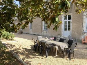 a table and chairs in front of a house at Le petit gîte du theil au servant in La Chapelle-Viviers +8 photos