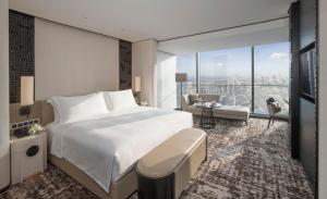 a bedroom with a large white bed and a living room at Jumeirah Nanjing in Nanjing
