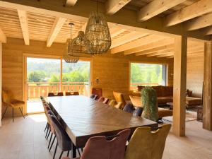 a dining room with a large wooden table and chairs at Chalet L'Oseraie, location touristique SPA 4 étoiles au cœur des Vosges in Le Saulcy